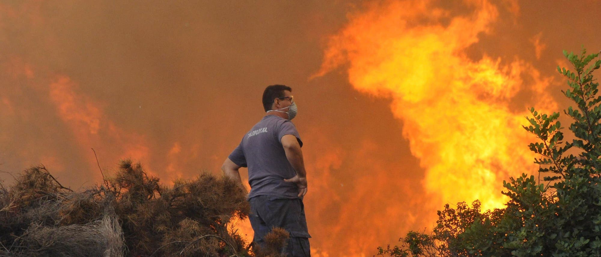 Ein Mann steht vor lodernden Flammen während eines Waldbrandes auf Rhodos Ein Mann steht vor lodernden Flammen während eines Waldbrandes auf Rhodos