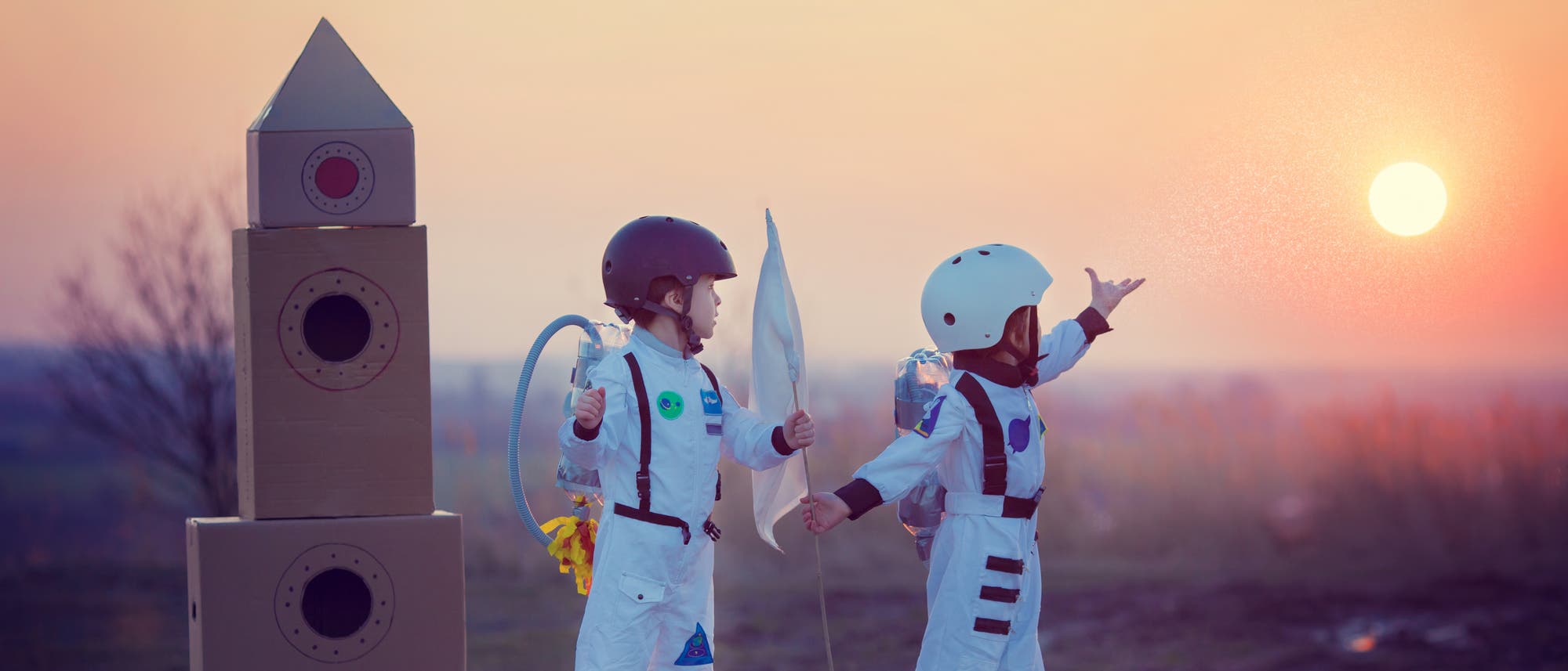 Zwei Kinder im Astronautenkostüm neben einer Rakete Zwei Kinder im Astronautenkostüm neben einer Rakete