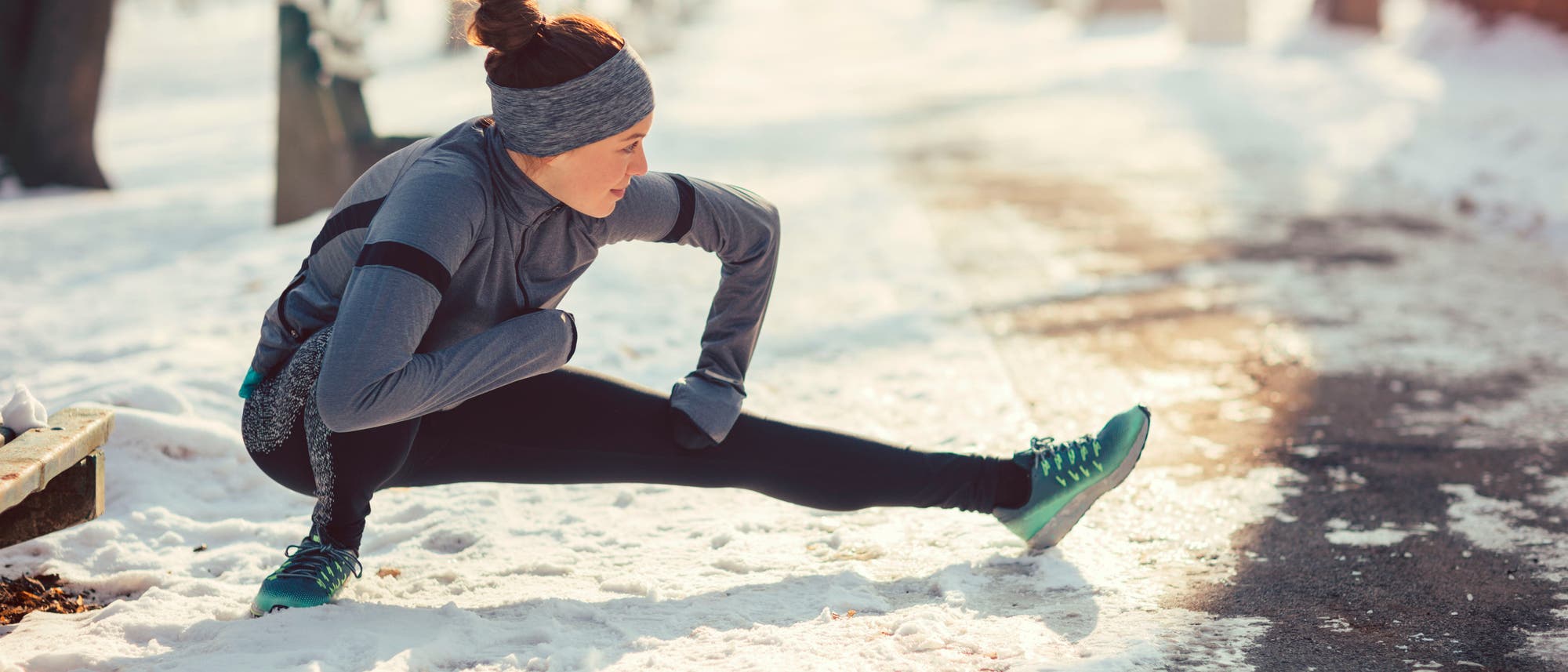 Eine Joggerin dehnt sich auf einem verschneiten Weg Eine Joggerin dehnt sich auf einem verschneiten Weg