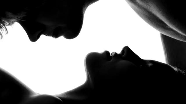 Schwarz-Weiß-Aufnahme von zwei Menschen – eine Person liegt auf dem Rücken, die zweite beugt sich von hinten über ihren Torso, dazwischen ist Weißraum