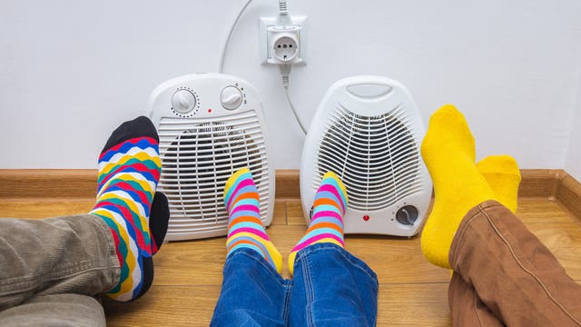 Füße mit bunten Socken vor zwei Heizlüftern.
