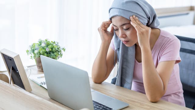 Gestresste Frau am Laptop mit Kopftuch